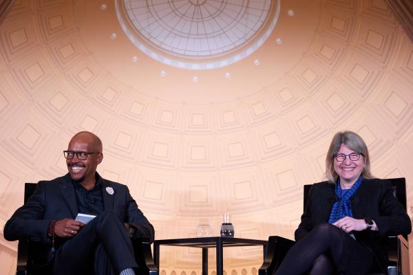 On the left R. Robert Wickham and on the right President Kornbluth sit on stage during a fireside chat in London.