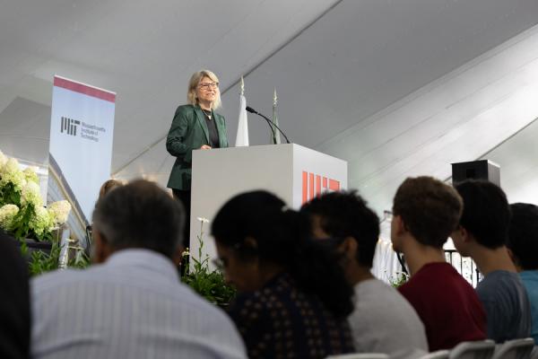 President Kornbluth stands behind a podium and in front of an MIT banner while welcoming the crowd and class of 2028.