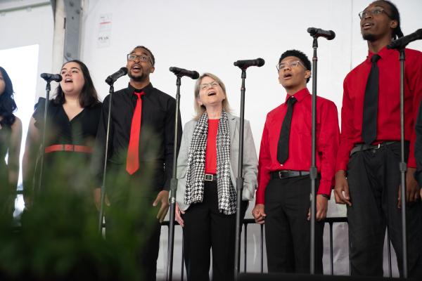 President Kornbluth stands in the middle of MIT's a cappella group and sings the school song with them.